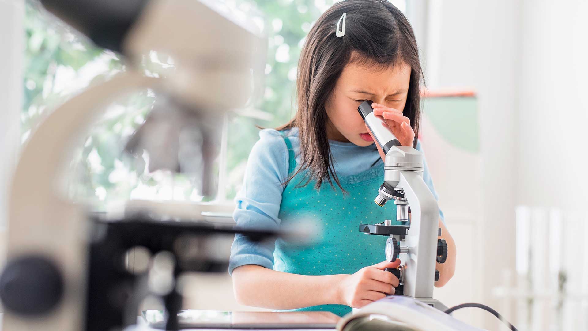 女孩用显微镜做实验；图片用于照顾您的家庭页面