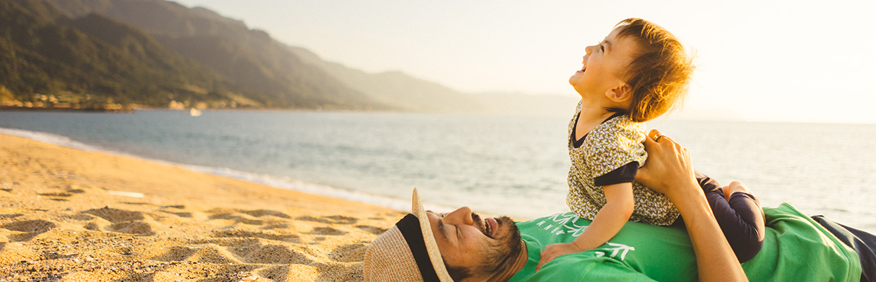 father and son lie on beach; the image used for wealth family
