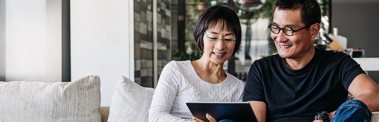 senior couple watching tablet on sofa ; the image used for understanding legacy planning