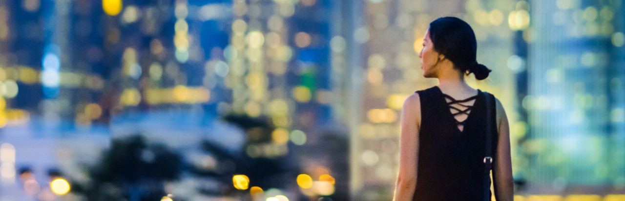 woman looking at night scenery of city; used for HSBC in greater China