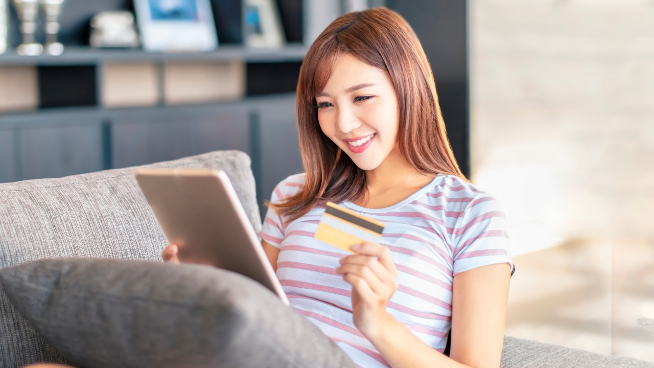 对着手机屏幕大笑的女孩;图片用于信用卡伴你尽情淘世界优惠