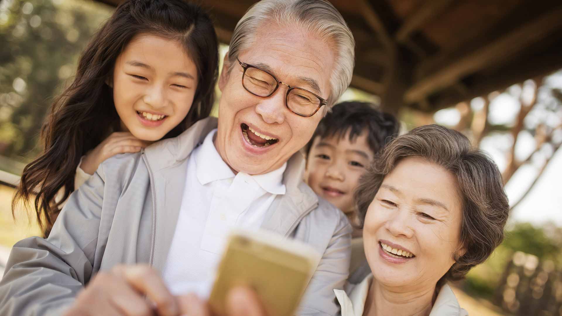 老人和孩子们在看智能手机；图片用于为老服务与儿童保护