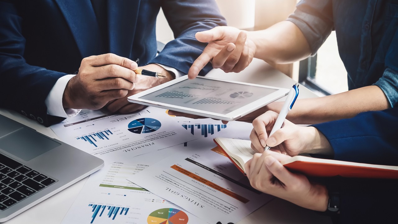people is discussing charts in tablet; the image used for Overseas Investment Plan