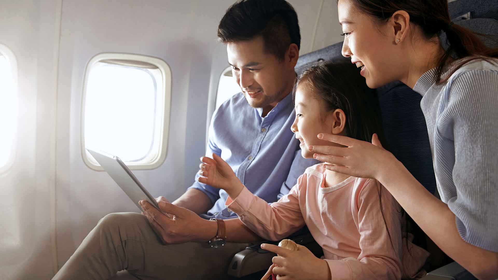 一家三口在飞机上看平板电脑；图片用于里程累积信用卡