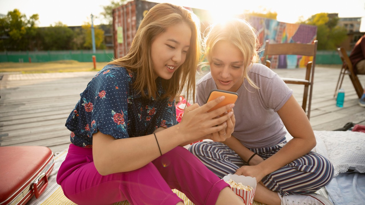 girls in the sunset browsing the phone, the image used for Foreign currency solutions