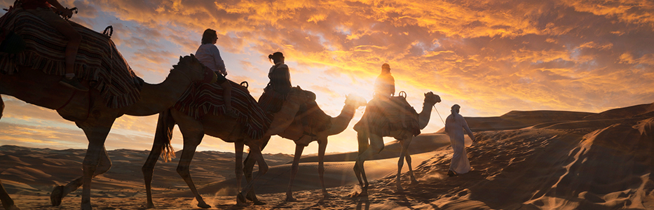 骑着骆驼在沙漠中游玩的游客