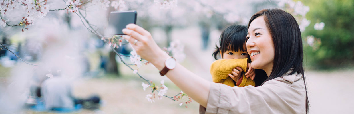 妈妈抱着女儿赏花；图片用于大都会人寿都会臻传终身寿险（分红型)