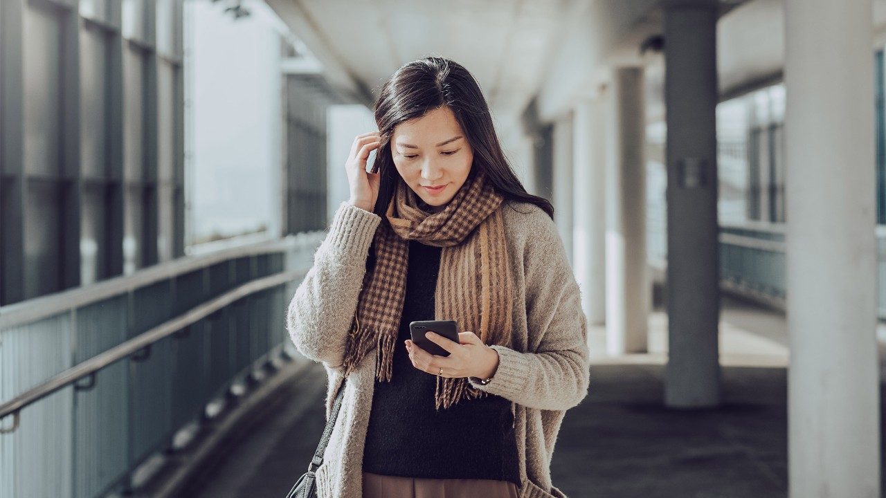 A girl looking at phone in bus stop; the image used for manage existing debt